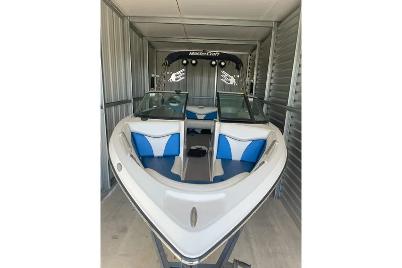 Slide: The Image of 2016 MasterCraft X10 boat on trailer, parked outside storage units. - 2