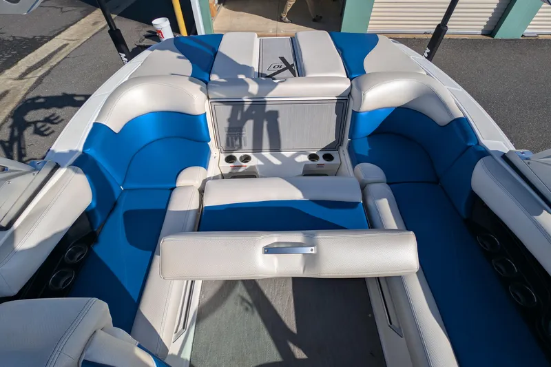 Slide: The Image of 2016 MasterCraft X10 boat interior with blue and white seating, cup holders, and storage compartments. - 31