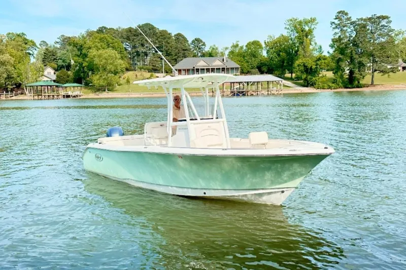 The Image of 2020 Sea Hunt Ultra 234 boat on a serene lake with lush greenery. - 0