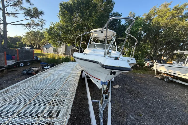 Slide: The Image of 2002 Century 2900 Walk-Around boat on trailer, surrounded by trees and equipment. - 23