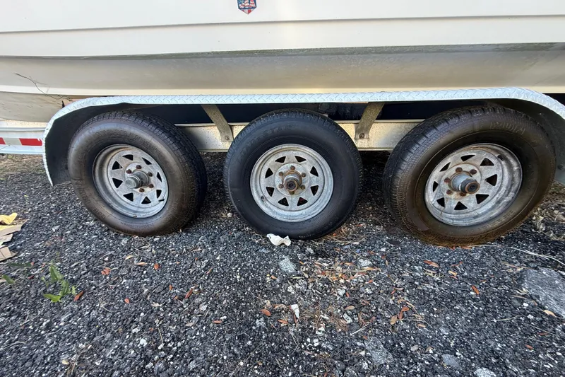 Slide: The Image of Trailer with three wheels for 2002 Century 2900 Walk-Around boat on gravel surface. - 47