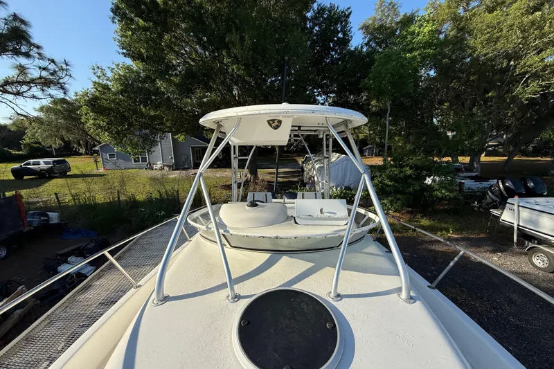 Slide: The Image of 2002 Century 2900 Walk-Around boat with T-top, parked outdoors near trees and vehicles. - 61