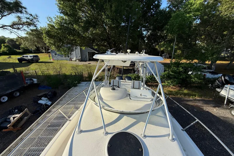 Slide: The Image of 2002 Century 2900 Walk-Around boat with T-top, parked outdoors near trees and vehicles. - 62