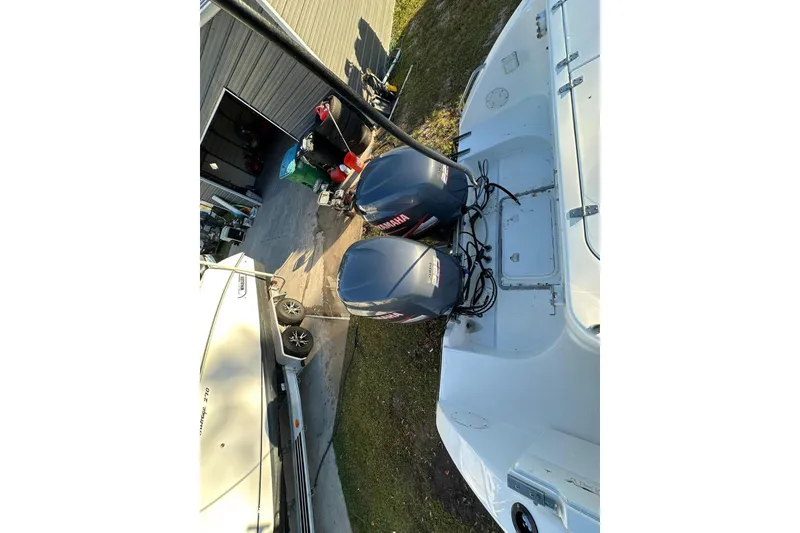 Slide: The Image of 2002 Century 2900 Walk-Around boat with dual Yamaha outboard motors, parked near a garage. - 7