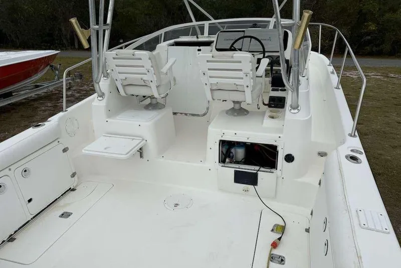 Slide: The Image of 2002 Century 2900 Walk-Around boat interior with dual helm seats and open storage compartment. - 77