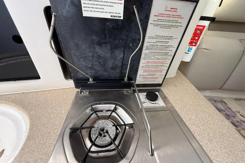 Slide: The Image of Stove in 2002 Century 2900 Walk-Around boat, featuring a single burner and safety instructions. - 97
