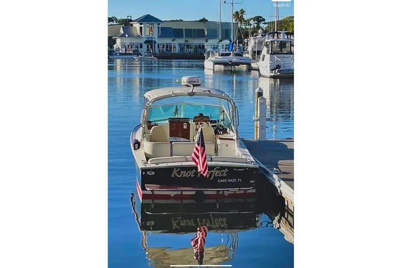 Slide: The Image of 2013 Hunt Yachts Harrier 25 docked, displaying an American flag, with marina backdrop. - 7