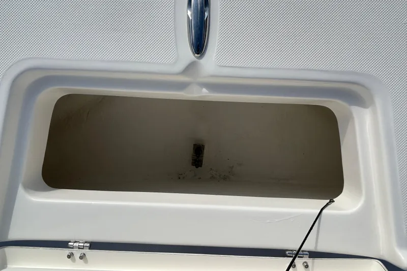 Slide: The Image of Open storage compartment on a 2026 Sundance DX22 boat, featuring a clean, white interior. - 12