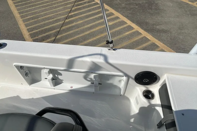 Slide: The Image of 2026 Sundance DX22 boat interior with seating and speaker, parked on asphalt. - 21