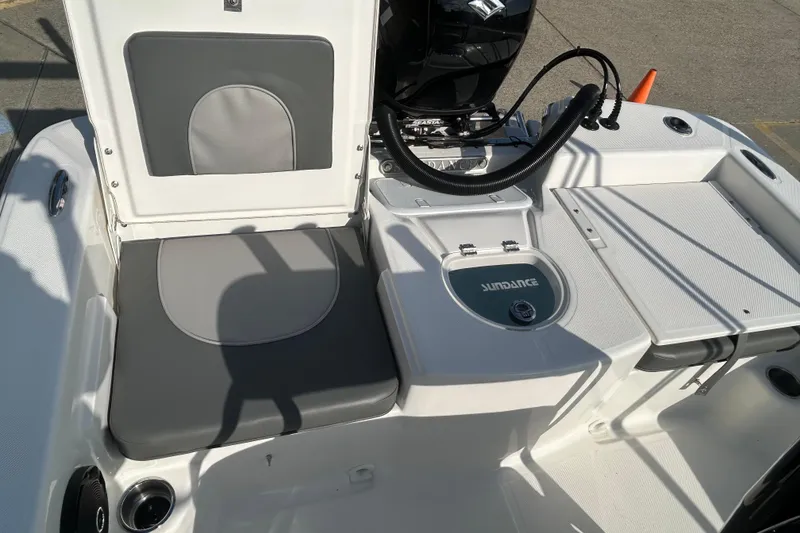 Slide: The Image of 2026 Sundance DX22 boat interior with seating and engine controls in sunlight. - 22