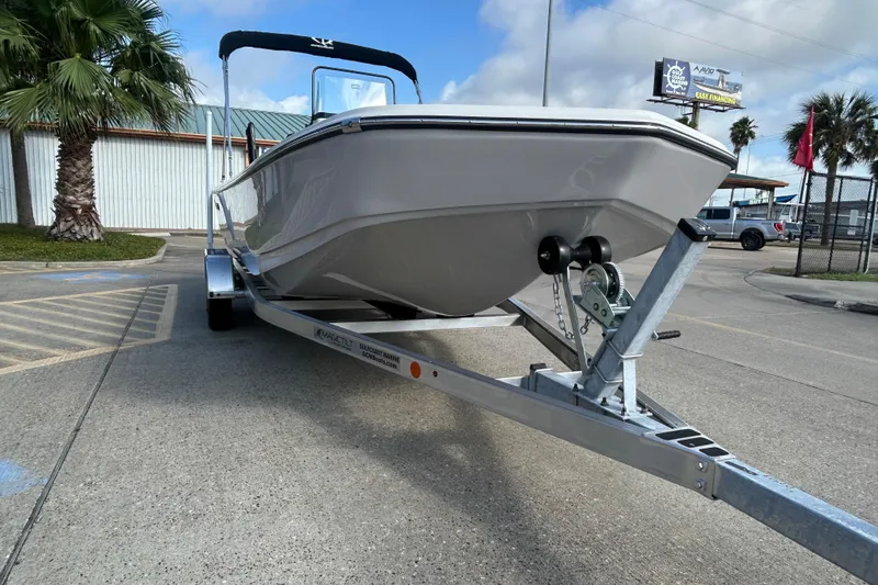 Slide: The Image of 2026 Sundance DX22 boat on trailer, parked outdoors under a blue sky. - 4