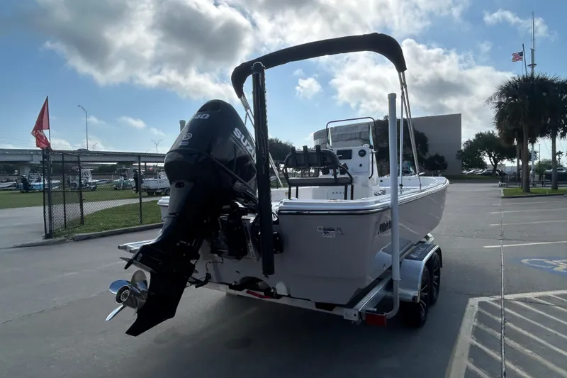 Slide: The Image of 2026 Sundance DX22 boat on trailer with Suzuki outboard motor in parking lot. - 8