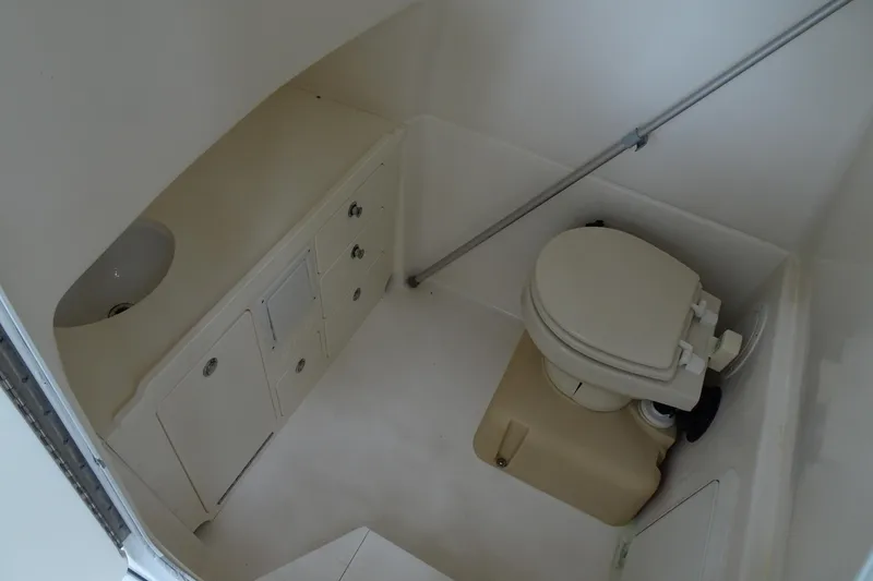 Slide: The Image of 2006 Edgewater 265CC boat interior with compact marine toilet and storage cabinets. - 27