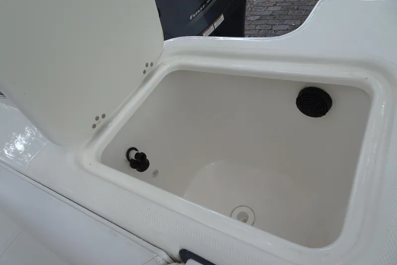 Slide: The Image of Open storage compartment on a 2006 Edgewater 265CC boat, featuring drainage and plug. - 28