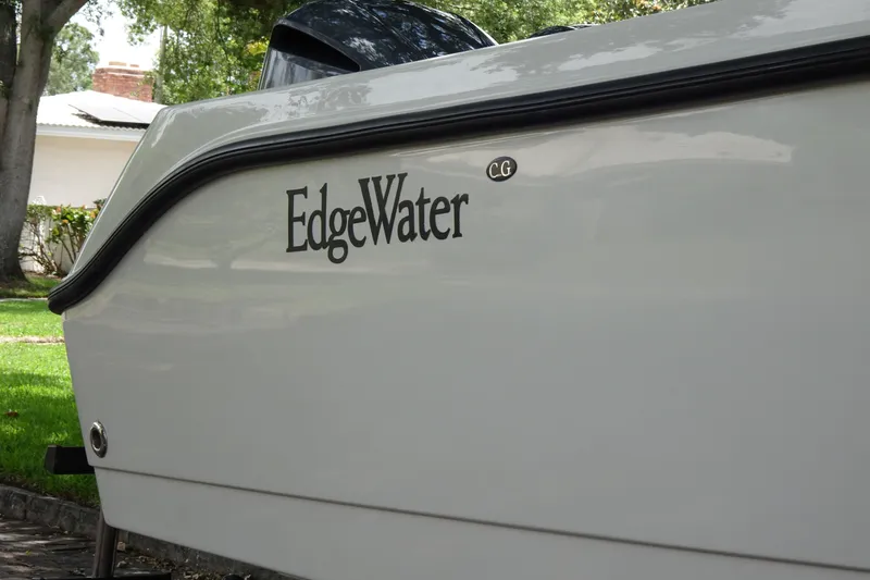 Slide: The Image of 2006 Edgewater 265CC boat side view with logo, parked outdoors. - 7