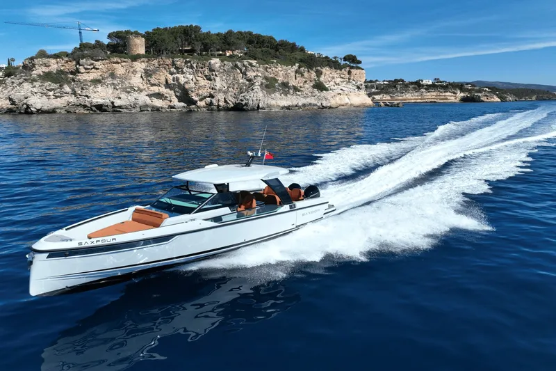 Slide: The Image of A 2027 Saxdor 320 GTO speeds across calm, blue water near a rocky coastline. - 36
