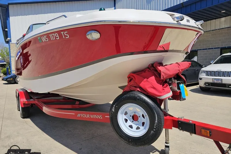 Slide: The Image of 2018 Four Winns HD220 boat on trailer, red and white exterior, parked outdoors. - 16