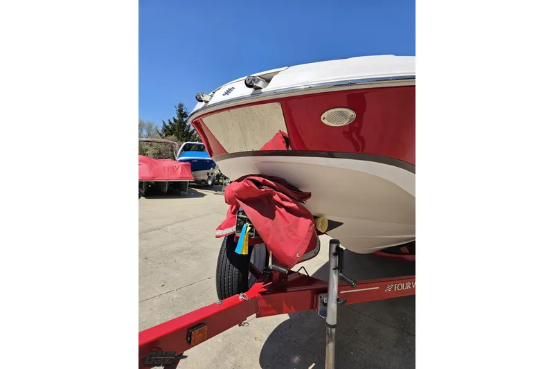 Slide: The Image of 2018 Four Winns HD220 boat on trailer, red and white hull, sunny day. - 20