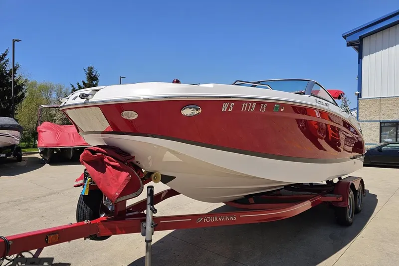Slide: The Image of 2018 Four Winns HD220 boat on trailer, red and white exterior, parked outdoors. - 21