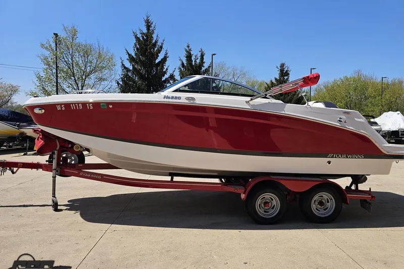 Slide: The Image of 2018 Four Winns HD220 boat on trailer, red and white, parked outdoors. - 24