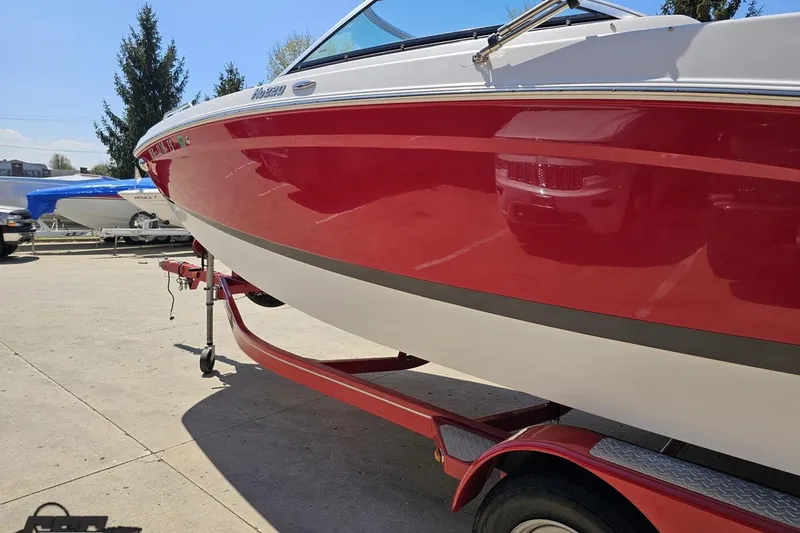 Slide: The Image of 2018 Four Winns HD220 boat in red on a trailer, parked outdoors. - 28
