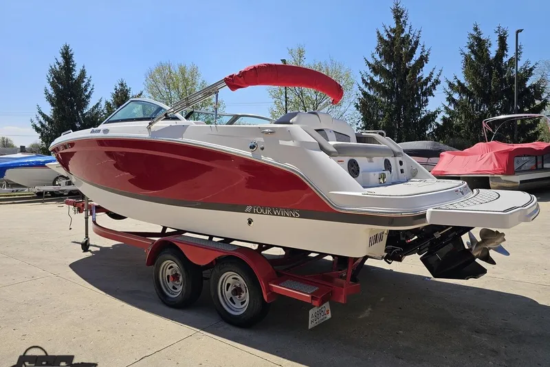 Slide: The Image of 2018 Four Winns HD220 boat on trailer, red and white design, parked outdoors. - 30