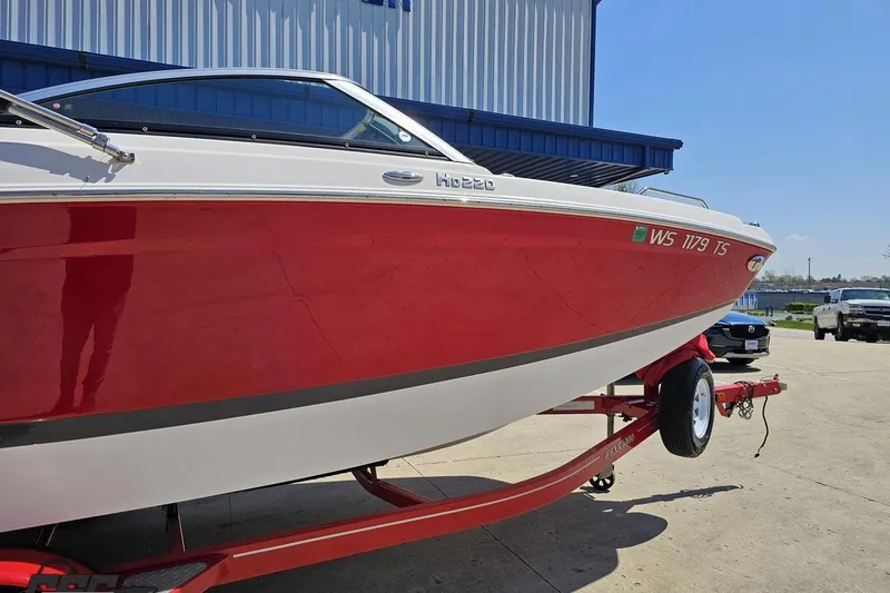 Slide: The Image of 2018 Four Winns HD220 boat in red and white on a trailer outside a building. - 4