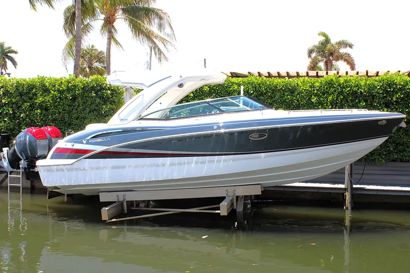 The Image of 2022 Formula 310 Bowrider OB boat docked near lush greenery and palm trees. - 0