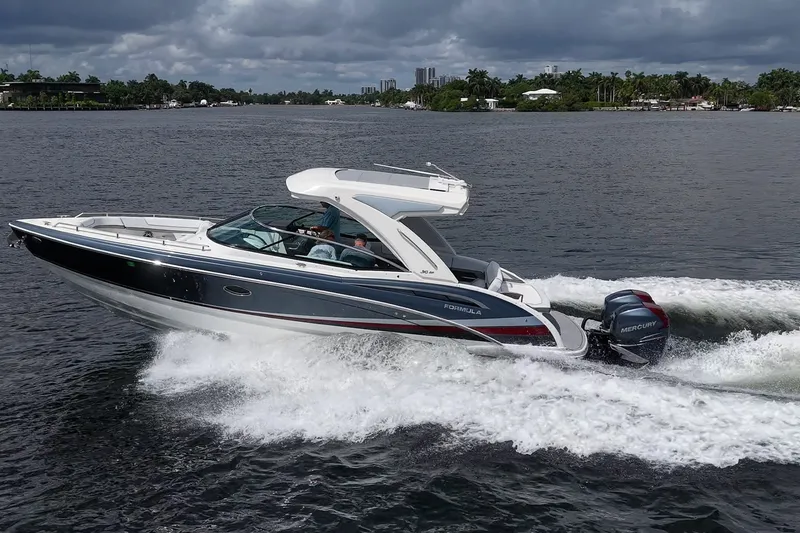 Slide: The Image of 2022 Formula 310 Bowrider OB cruising on a scenic waterway under cloudy skies. - 15