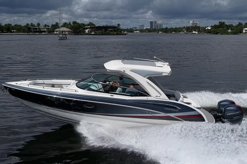 Slide: The Image of 2022 Formula 310 Bowrider OB cruising on a scenic waterway under cloudy skies. - 17