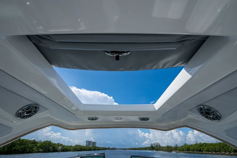 Slide: The Image of 2022 Formula 310 Bowrider OB boat with open sunroof, showcasing blue sky and water view. - 61