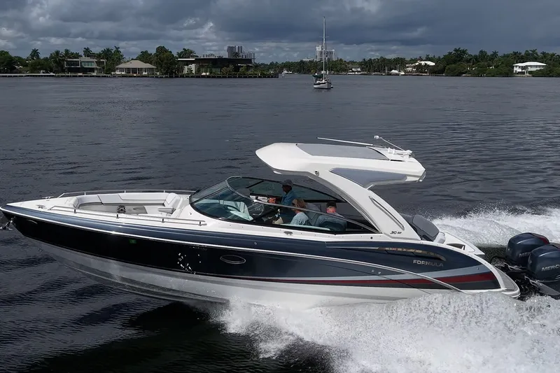 Slide: The Image of 2022 Formula 310 Bowrider OB cruising on a scenic waterway under cloudy skies. - 18