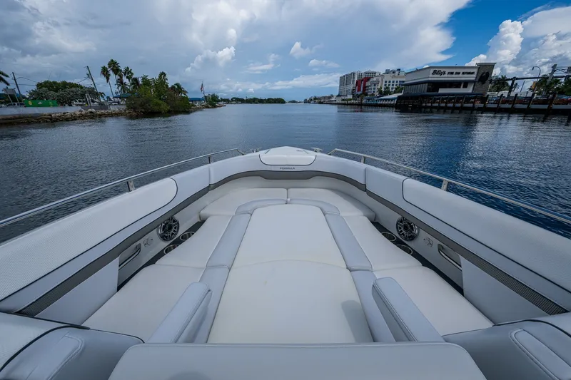 Slide: The Image of 2022 Formula 310 Bowrider OB boat with spacious seating, docked by a scenic waterfront. - 65