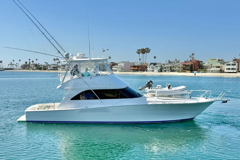 The Image of 2002 Viking 48 Convertible yacht on calm water near a coastal neighborhood. - 0