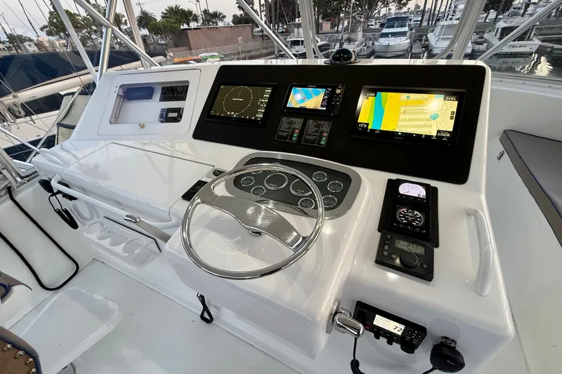 Slide: The Image of Control panel of a 2002 Viking 48 Convertible yacht with navigation screens and steering wheel. - 12