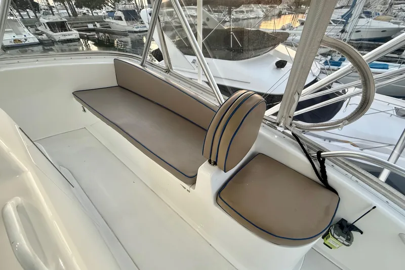 Slide: The Image of Interior seating of 2002 Viking 48 Convertible yacht, featuring beige cushions with blue piping. - 15