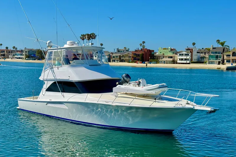 Slide: The Image of 2002 Viking 48 Convertible yacht on calm water near a coastal neighborhood. - 3