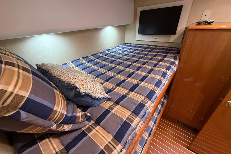 Slide: The Image of Cozy cabin interior of 2002 Viking 48 Convertible with plaid bedding and wall-mounted TV. - 45