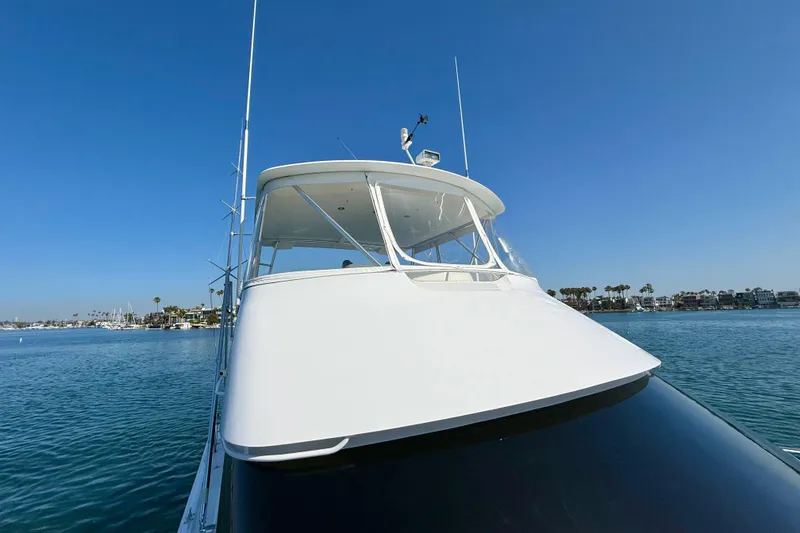 Slide: The Image of 2002 Viking 48 Convertible yacht on calm water under clear blue sky. - 58