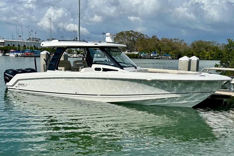The Image of 2023 Boston Whaler 350 Realm boat docked on calm water under cloudy sky. - 0
