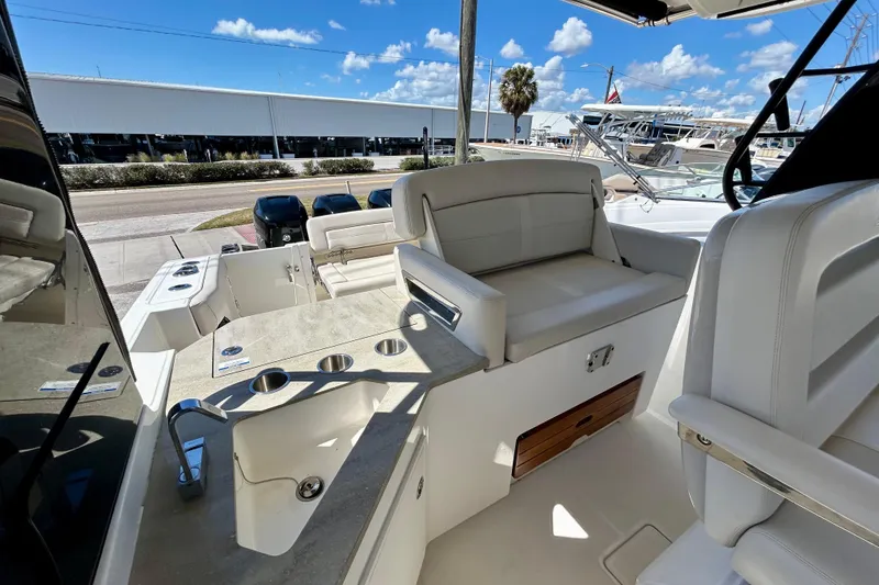 Slide: The Image of 2023 Boston Whaler 350 Realm interior with seating and sink, under a clear blue sky. - 11