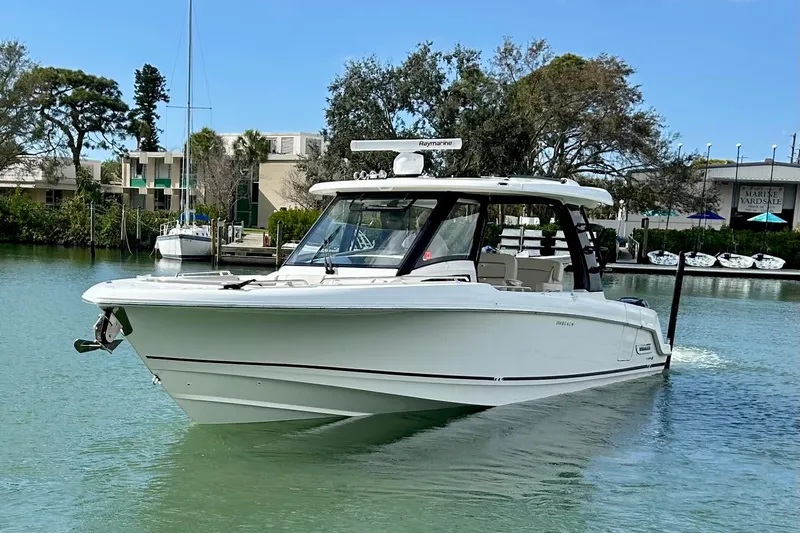 Slide: The Image of 2023 Boston Whaler 350 Realm cruising on a calm waterway, surrounded by greenery. - 2