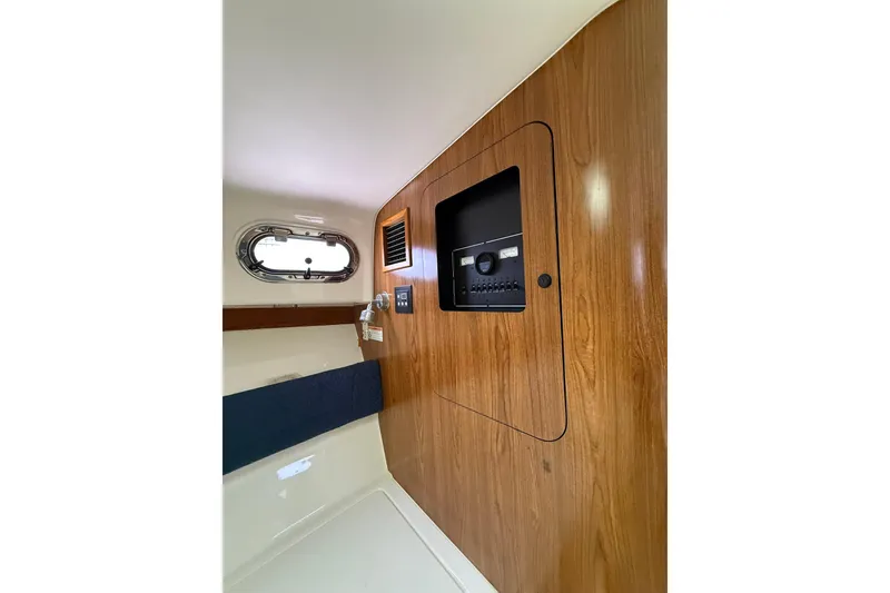 Slide: The Image of Interior cabin of 2012 Pursuit OS 315 Offshore boat with wood paneling and porthole. - 12