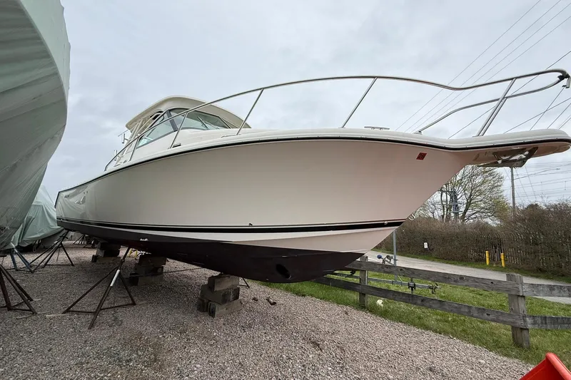 Slide: The Image of 2012 Pursuit OS 315 Offshore boat on dry dock, side view, overcast sky. - 2