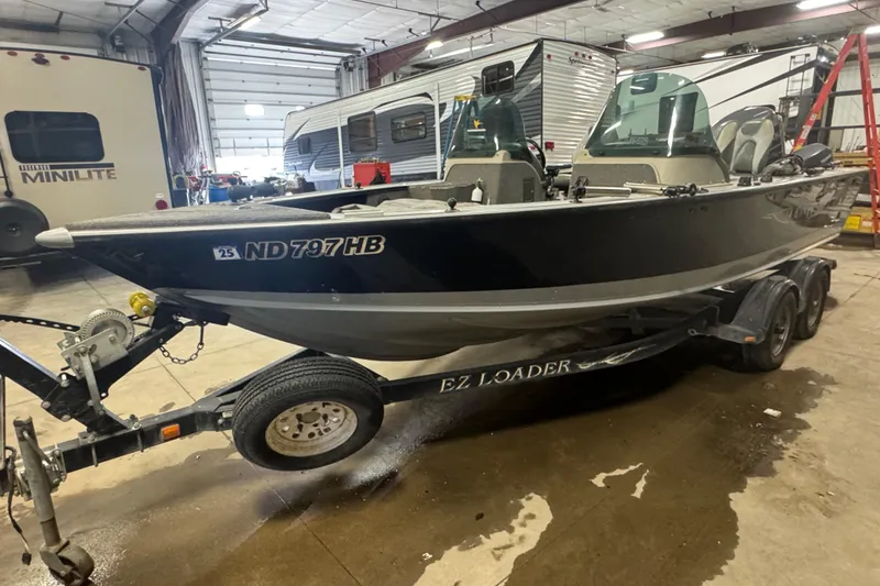 The Image of 2003 Lund 2025 Pro-V Magnum IFS boat on trailer in garage setting. - 0