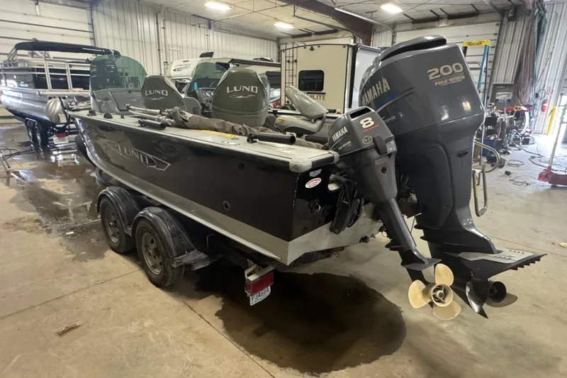 Slide: The Image of 2003 Lund 2025 Pro-V Magnum IFS boat with Yamaha outboard motors in a garage setting. - 2