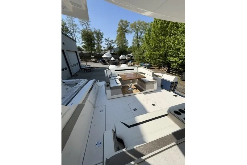 Slide: The Image of 2022 Tiara Yachts 43 LS deck with seating area and table, surrounded by trees. - 3