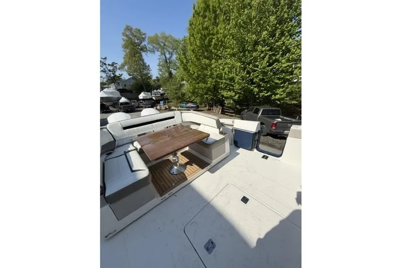 Slide: The Image of 2022 Tiara Yachts 43 LS deck with seating and wooden table, surrounded by trees. - 4