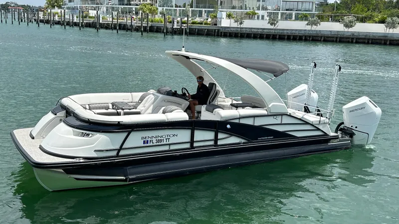 The Image of 2024 Bennington QX Line pontoon boat on calm water with modern design and twin outboard engines. - 0