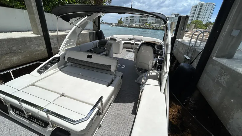 Slide: The Image of 2024 Bennington QX Line luxury pontoon boat docked by the water. - 20